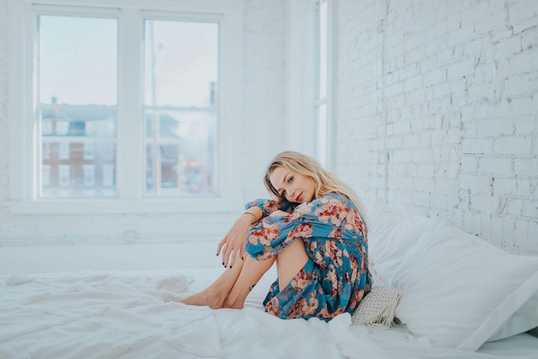 woman-wearing-floral-dress-while-sitting-on-bed-3586911-1