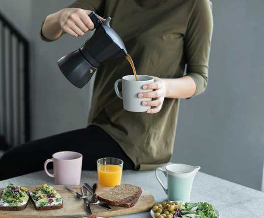woman-in-green-top-pouring-coffee-in-a-white-mug-3754296